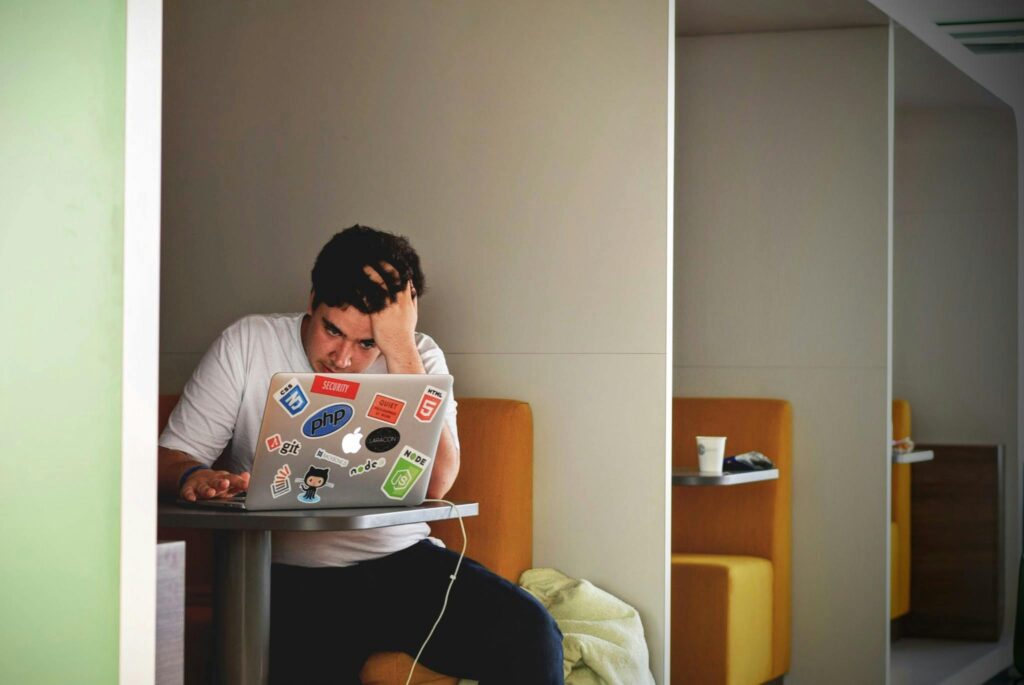 Man showing stress and frustration while working remotely on a laptop indoors.